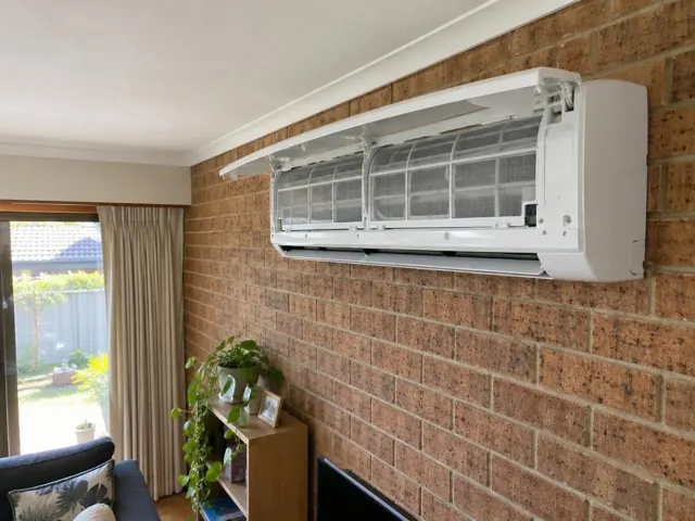 Clean split system on a brick wall with open front panel and visible filters in a living room in Salisbury North