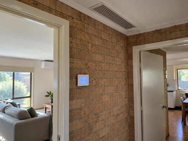 Ceiling return air grille and wall controller on a brick interior wall in a home in Salisbury Plain